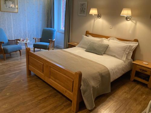 a bedroom with a large bed with two blue chairs at Chambres & Table d'hôtes de La Vieille Ferme in Salon-la-Tour