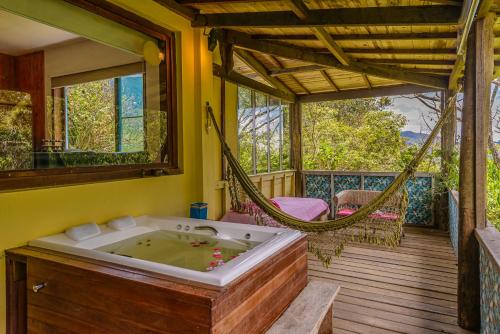 een badkamer met een hangmat en een bad op een veranda bij Pousada Mandala das Águas in Aiuruoca