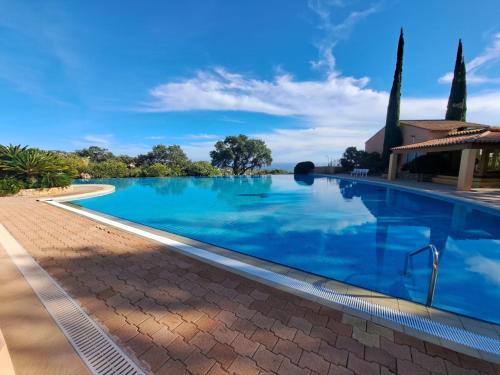 una piscina in una villa con acqua blu di APPARTEMENT CLIMATISE - TERRASSE AVEC APERCU MER - GOLF DE ST TROPEZ a Les Issambres