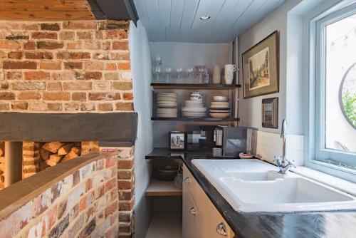 a kitchen with a sink and a brick wall at Old Chelsea in Deal