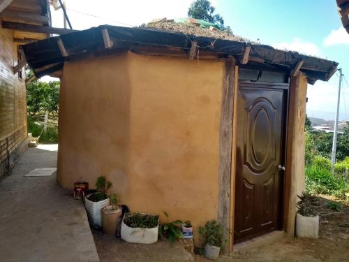 a small house with a brown door and potted plants at Casa de Barro Ecodomo in Los Santos
