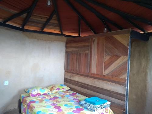 a bed in a room with a wooden wall at Casa de Barro Ecodomo in Los Santos