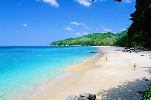 a beach with people walking on the sand and the ocean at Beachfront 2br home with private plunge pool on stunning Naithon beach 3 in Nai Thon Beach