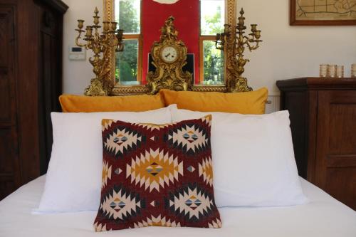 a bed with white pillows and a clock on the wall at Authentieke privé-kamer bij Karen in Beveren