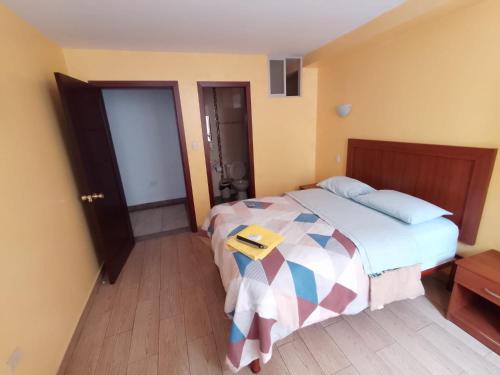 een slaapkamer met een bed met een boek erop bij Hotel Residencial Miraflores in Loja