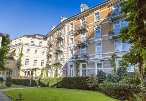 an apartment building with a lawn in front of it at HELIOPARK Bad Hotel Zum Hirsch in Baden-Baden