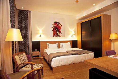 a hotel room with a bed, chair, lamp, and nightstand at Misafir Suites 8 Istanbul in Istanbul