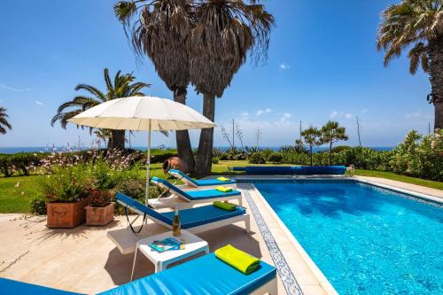 una mujer sentada en una silla junto a una piscina en Casa Piranhas, en Carvoeiro