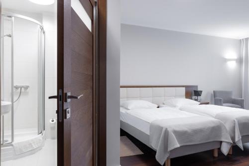 a bedroom with a bed and a glass door at Kolumna Park Hotel in Dobroń