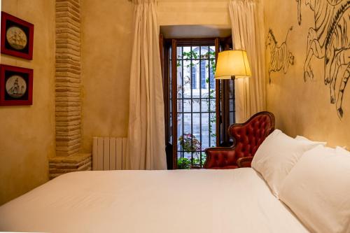 a bedroom with a bed and a chair and a window at Casa Palacio Rincón de la Catedral in Toledo