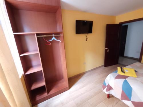 Habitación con armario, TV y cama. en Hotel Residencial Miraflores, en Loja