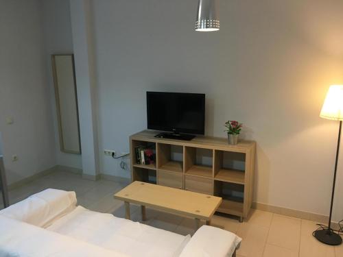 ein Wohnzimmer mit einem TV und einem Tisch in der Unterkunft Apartamentos El Palo in Málaga