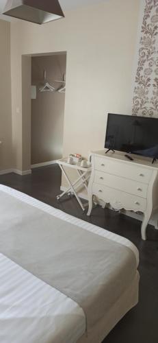 a bedroom with a bed and a tv and a desk at L'Heure Bleue gîtes et chambres d'hôtes in Givenchy-en-Gohelle
