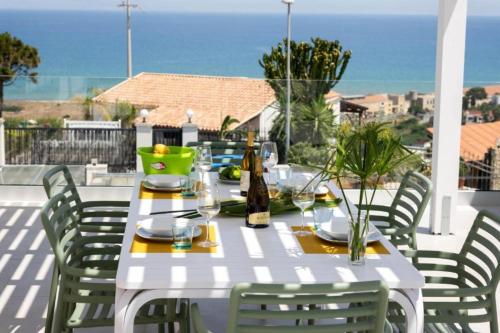 a white table with chairs and wine bottles on a patio at Villa Taliala in Alcamo Marina