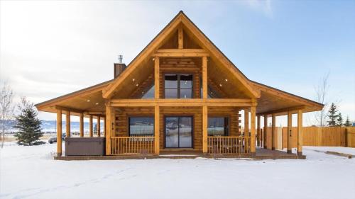 a log cabin in the snow with a large window at Targhee Shadows - Tetons Yellowstone hot tub in Tetonia