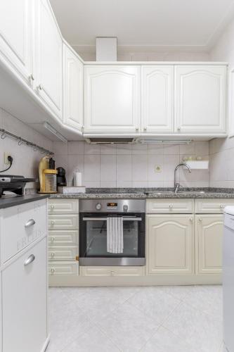 a white kitchen with white cabinets and an oven at Nice Apartment with Veranda in Gaia - 3D in Vila Nova de Gaia
