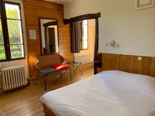 a bedroom with a bed and a chair and windows at Au Sans Souci in Saint-Paul-lès-Monestier