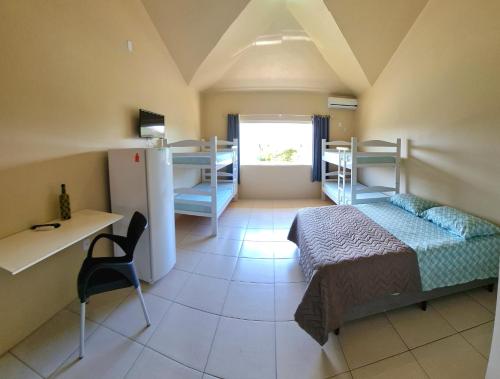 a bedroom with a bed and a desk and a room with bunk beds at Pousada Girassol da Ferrugem in Garopaba