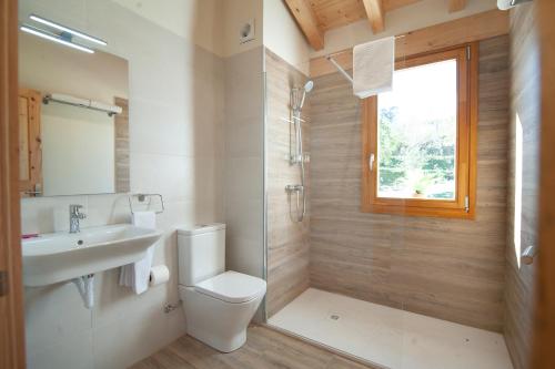a bathroom with a toilet and a sink and a window at La Asomada de Vidular in Bárcena de Cicero