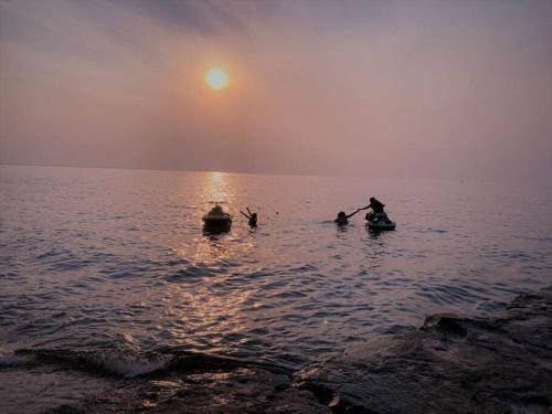 a group of people in the water at sunset at Modern Beach House long stay discounts in Sarnia