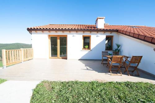 a white house with a patio with chairs and a table at La Asomada de Vidular in Bárcena de Cicero