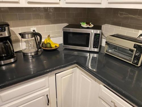 a kitchen counter with a microwave and a bowl of fruit at Modern Beach House long stay discounts in Sarnia