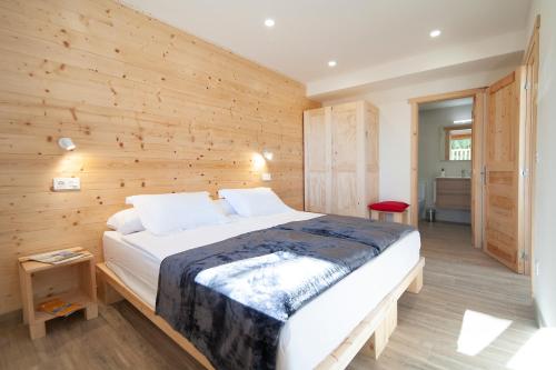 a bedroom with a large bed in a wooden wall at La Asomada de Vidular in Bárcena de Cicero