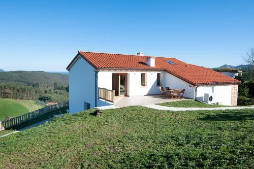 a small house on top of a grassy hill at La Asomada de Vidular in Bárcena de Cicero
