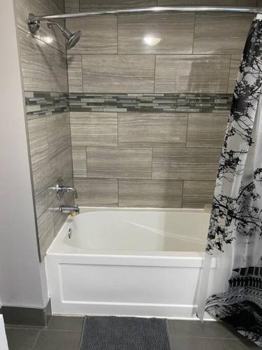 a white bath tub in a bathroom with a shower at Modern Beach House long stay discounts in Sarnia