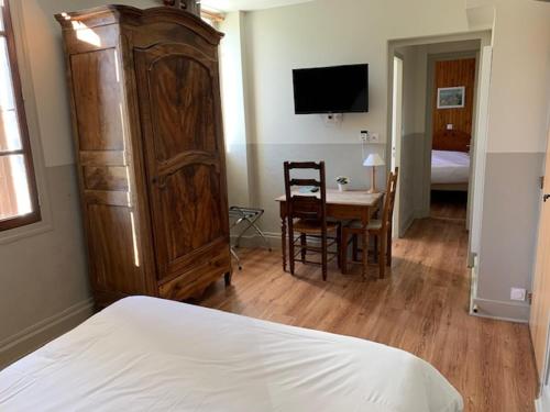 a bedroom with a large wooden cabinet next to a bed at Au Sans Souci in Saint-Paul-lès-Monestier