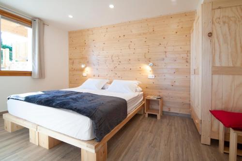 a bedroom with a large bed with a wooden wall at La Asomada de Vidular in Bárcena de Cicero