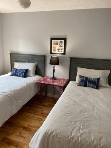 a bedroom with two beds and a table with a lamp at Modern Beach House long stay discounts in Sarnia