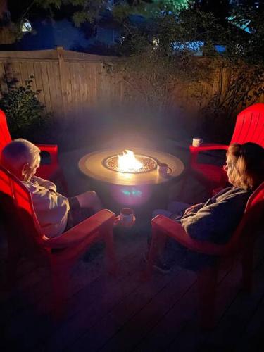 a couple of people sitting in chairs around a fire pit at Modern Beach House long stay discounts in Sarnia