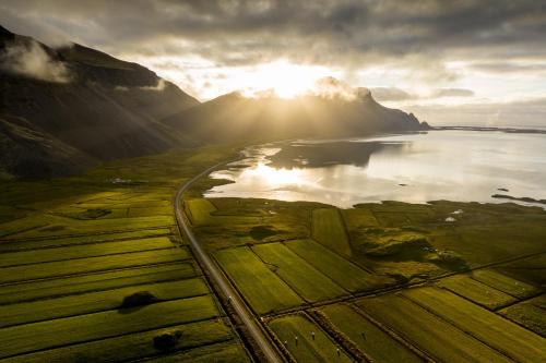 an aerial view of a lake and mountains with the sun shining at Árnanes Country Hotel in Höfn