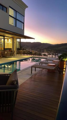 a house with a swimming pool and chairs on a deck at Vista do Lago Hotel in Capitólio