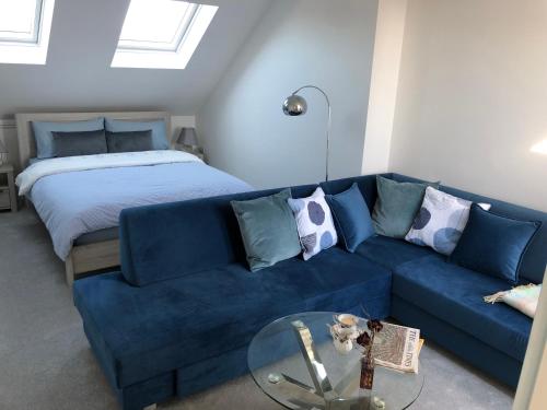 a living room with a blue couch and a bed at Ainslie Loft in Chingford, London in Chingford