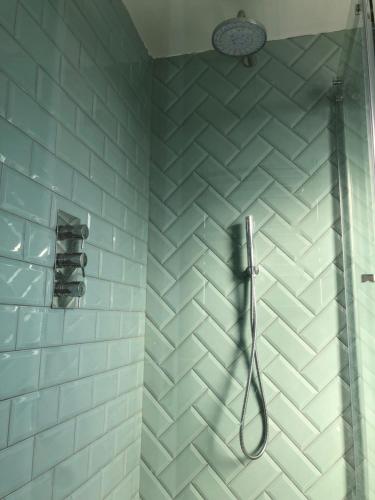 a bathroom with a shower with blue and white tiles at Ainslie Loft in Chingford, London in Chingford