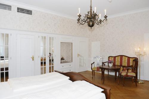a bedroom with two beds and a table and a chandelier at HELIOPARK Bad Hotel Zum Hirsch in Baden-Baden