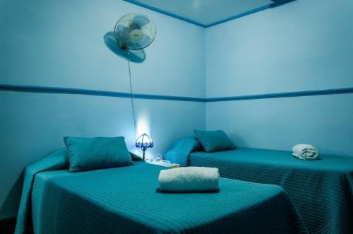 Habitación azul con 2 camas y ventilador. en Casa Sahari Appartement 3, en La Habana