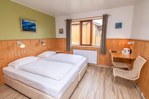 a bedroom with a bed and a desk and a window at Árnanes Country Hotel in Höfn