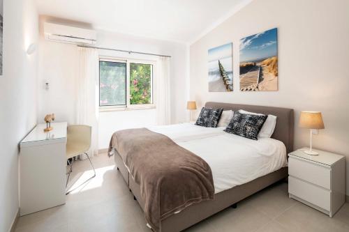 a bedroom with a bed and a desk and two windows at Casa Guincho in Carvoeiro