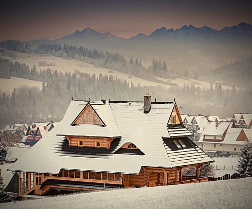 a house covered in snow with mountains in the background at Willa Jarząbek - 5 min do term Szaflary I Gorący Potok in Szaflary