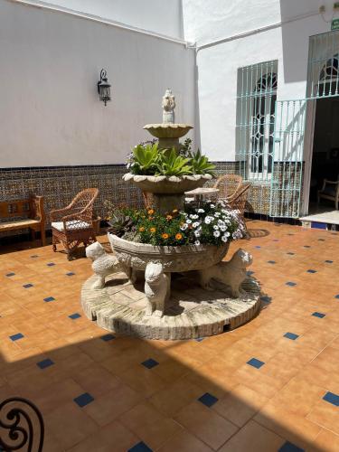 a fountain in the middle of a room with flowers at HOSTAL LA CRUZ 1872 in Chipiona