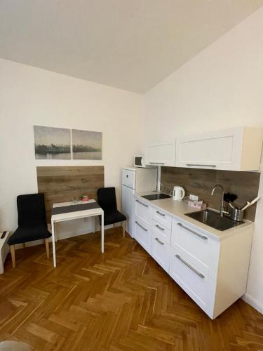 een keuken met witte kasten, een wastafel en een tafel bij Apartmen -Studio in Praag