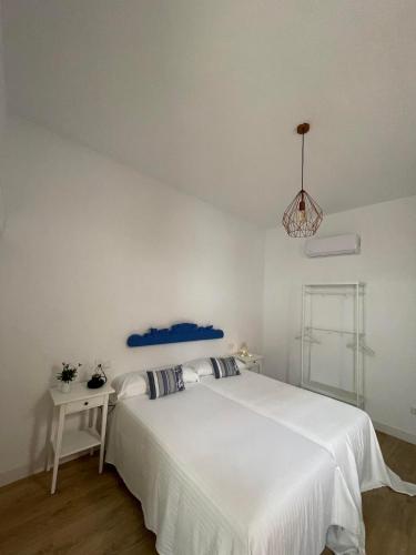 a white bedroom with a white bed and a table at HOSTAL LA CRUZ 1872 in Chipiona