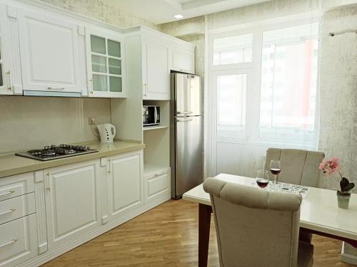 a kitchen with white cabinets and a table with a glass of wine at 3 комнатная VIP квартира возле метро in Baku