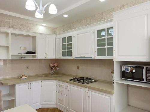 a white kitchen with white cabinets and a microwave at 3 комнатная VIP квартира возле метро in Baku