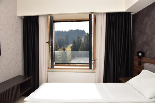 a hotel room with a bed and a window at Woodside Kopaonik Residences in Kopaonik