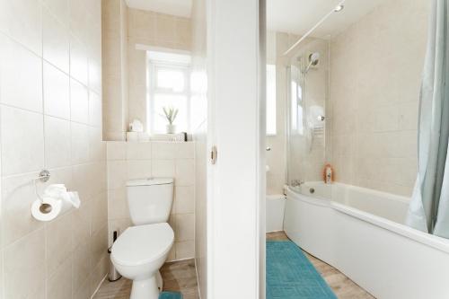 a white bathroom with a toilet and a bath tub at Stepney Green beds to stay 24 in London