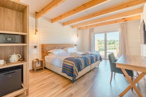 a bedroom with a bed and a desk and a television at Sleep & Nature Hotel in Lavre